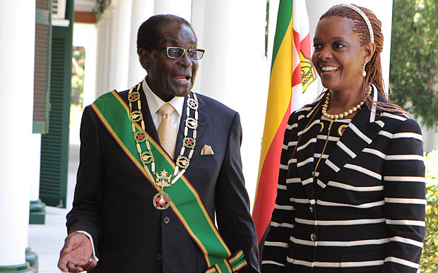 Zimbabwe President Robert Mugabe stands with his wife Grace, as they pose for a photo at State House in Harare, Tuesday, Oct, 28, 2014.  Muagbe officially opened the first session of the 8th parliament of Zimbabwe in Harare where he called on the government to deal with the ever rising housing backlog across the country. (AP Photo/Tsvangirayi Mukwazhi)